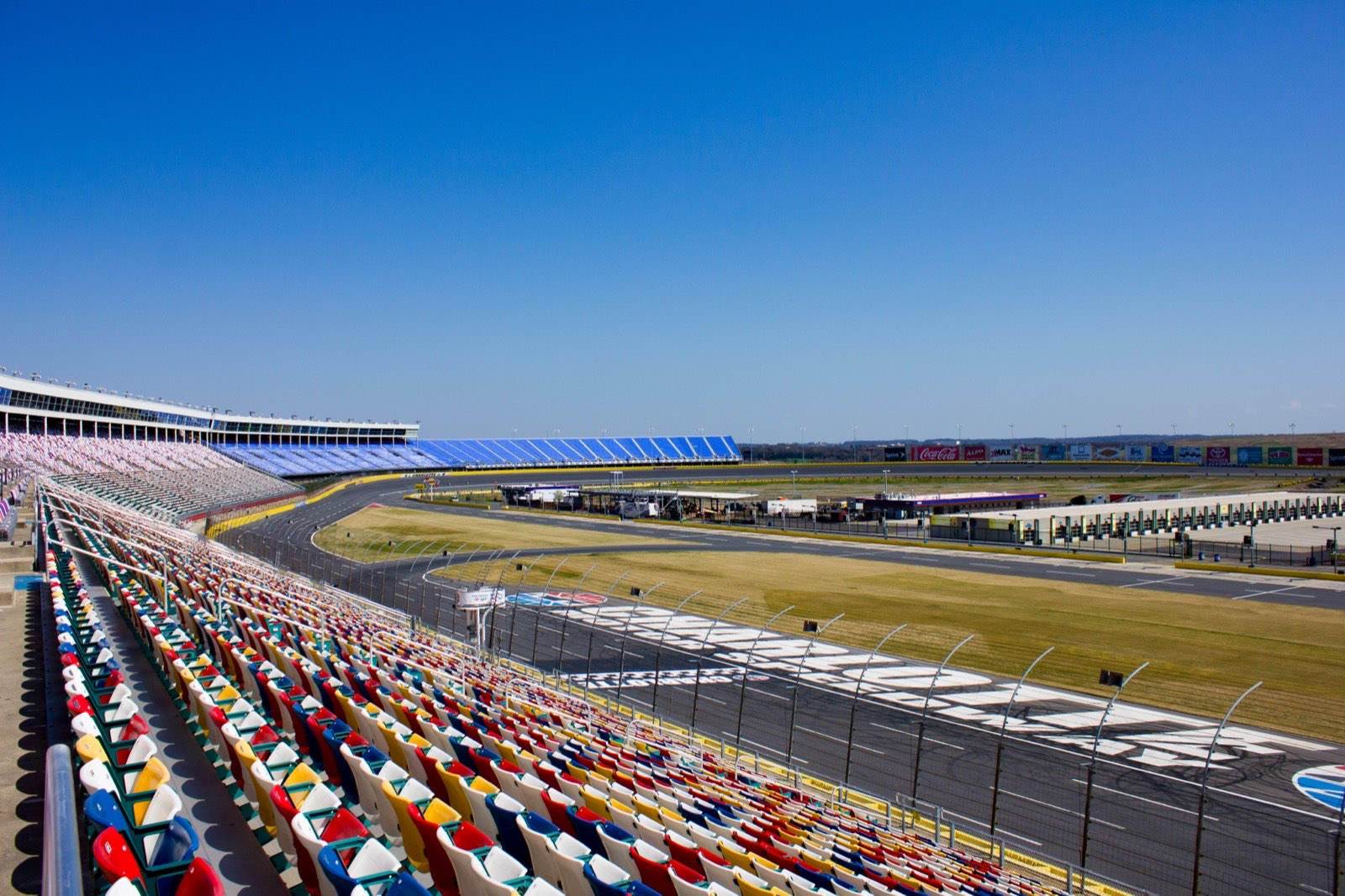 Rows of empty red, blue, yellow and white grandstand seats overlooking the frontstretch and tri-oval banking at Charlotte Motor Speedway in Concord, North Carolina