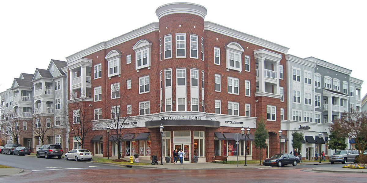 Four-story brick mixed-use building with ground-floor shops and upper-floor apartments at the corner of Birkdale Village in Huntersville, North Carolina