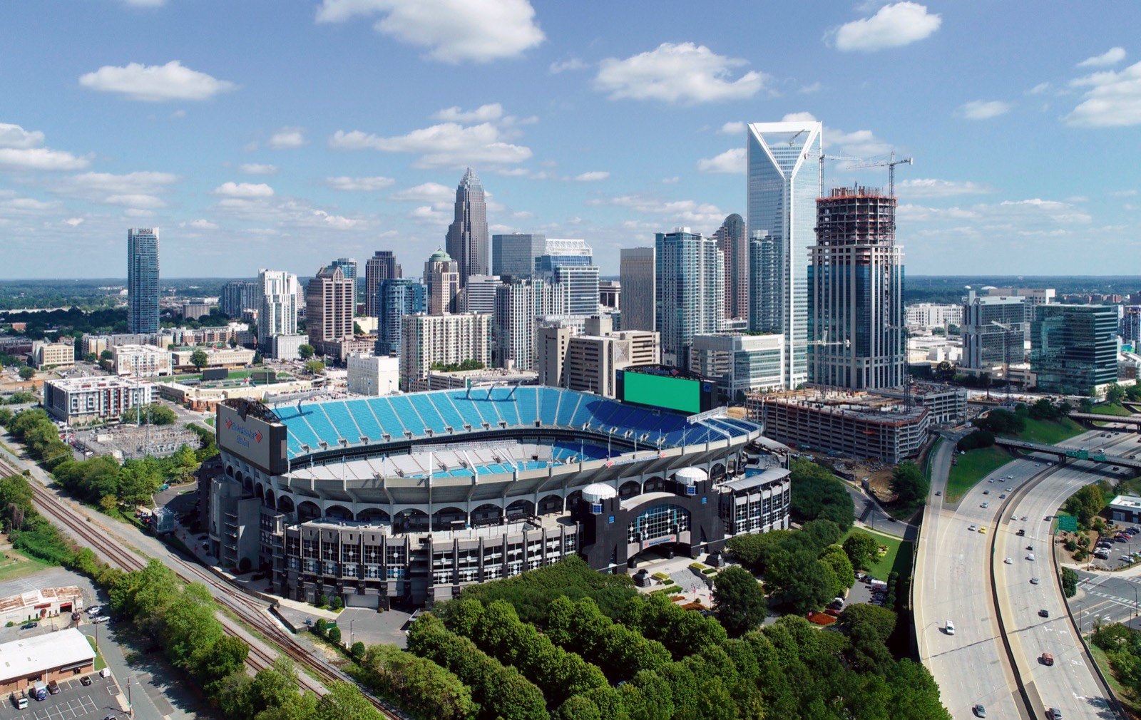 Aerial view of Bank of America Stadium in Charlotte, North Carolina, with the Uptown skyline behind it including the Bank of America Corporate Center and Duke Energy Center